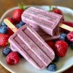 ['Close-up view of colorful homemade popsicles with yogurt and mixed berries.', 'Side view of refreshing yogurt popsicles garnished with strawberries, blueberries, and raspberries.', 'Brightly colored popsicles made from yogurt, mixed berries, and drizzled honey.', 'Homemade popsicles displayed in a row, showcasing vibrant berry colors and creamy yogurt.']