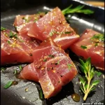 Close-up of juicy thon à la plancha garnished with herbs.