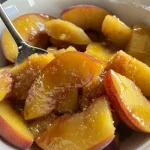 Close-up view of a vibrant bowl of nectarine compote, showcasing juicy fruit pieces.