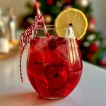 Gros plan d'un cocktail de Noël aux cranberries avec une paille rouge et blanche.